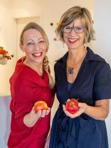 奥登塔尔埃堪佩霍赫酒店的两个女人站在对方旁边,拿着苹果