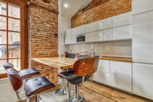 图卢兹Charming and luxury flat in Toulouse - Welkeys的厨房设有砖墙和木桌及椅子