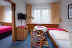 新勃兰登堡Hotel Horizont GmbH的客房设有两张床、一张桌子和一台电视机。