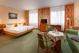 新勃兰登堡Hotel Horizont GmbH的酒店客房带一张床、一张桌子和椅子