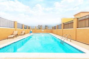 Rockdale德克萨斯洛克达尔戴斯酒店的一座酒店游泳池,旁边设有两把椅子