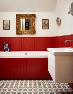ResolisNewhall Mains的红色的浴室设有浴缸和镜子