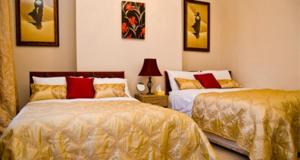 多佛尔7号修道院旅馆的一间卧室配有两张带金色和红色枕头的床