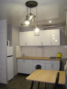 切尔尼戈夫Квартира студия в центре Чернигова wi-fi的厨房配有白色橱柜和木桌