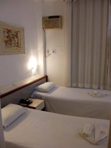 贝洛奥里藏特Hotel Pampulha Palace的酒店客房设有两张床和窗户。