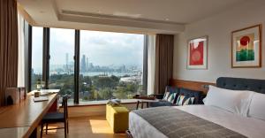 香港Little Tai Hang 酒店及服务式公寓的酒店客房设有一张床、一张书桌和一个大窗户。