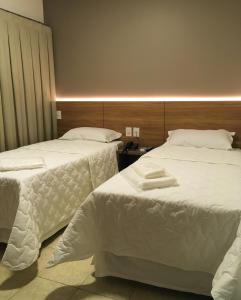 乌贝兰迪亚Hotel Alpha的配有白色床单的酒店客房内的两张床