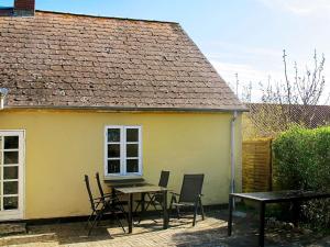班霍尔姆4 person holiday home in Bandholm的黄色房子前面的一张桌子和椅子