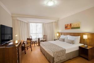 巴西利亚Windsor Plaza Brasilia的酒店客房带一张床、一张桌子和椅子