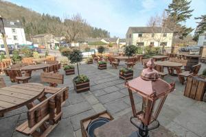普利布里奇The Pooley Bridge Inn的庭院设有木桌、长椅和树木