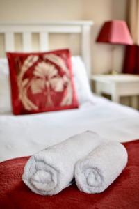霍利黑德维清汉姆住宿加早餐旅馆的床上的两条毛巾和红色枕头