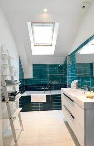拉波勒Chez Lilette的浴室铺有绿色瓷砖,设有天窗。