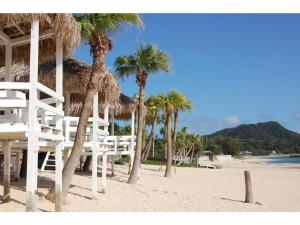 奄美Amami Resort Bashayamamura / Vacation STAY 81475的海滩上拥有棕榈树和白色椅子的海滩