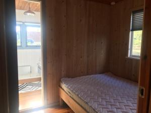 埃贝尔托夫特Hyggeligt sommerhus i Ebeltoft, tæt på strand og skov.的木制客房内的一间卧室,配有一张床
