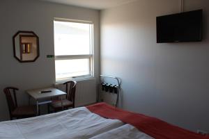 霍夫索斯苏娜伯格宾馆的一间卧室配有一张床、一张桌子和一个窗户。