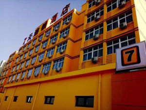 天津7天酒店·天津交通学院曹庄地铁站店的一座黄色的大建筑,前面有标志