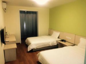 天津7天酒店·天津交通学院曹庄地铁站店的酒店客房设有两张床和电视。