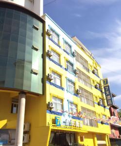 景洪市7天酒店·西双版纳嘎洒机场客运南站店的黄色建筑,有玻璃幕墙