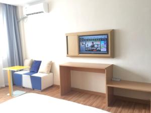 7天酒店·赣州会昌昌寿店的一间设有床铺和墙上电视的房间