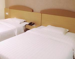武汉7天武汉武昌火车站地铁站店的酒店的客房内设有两张白色的床,配有电话