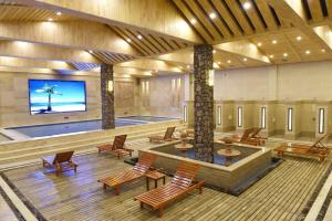 葫芦岛7天酒店葫芦岛兴城大学城店的大型大堂设有游泳池、椅子和电视