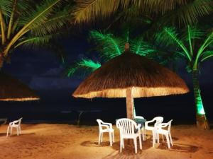 本托塔Oasey Ayurveda Hotel的海滩上草伞下的桌椅