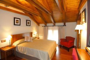 卡斯特洪德索斯蒂亚莫酒店的一间卧室配有一张大床和一张红色椅子