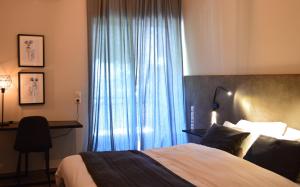 卢特拉伊帕蒂斯Alexakis Hotel & Spa的一间卧室配有一张床、一张书桌和一个窗户。