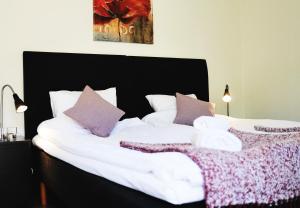 Kågeröd卡格罗兹三星宾馆的一间卧室配有两张床、白色床单和紫色枕头