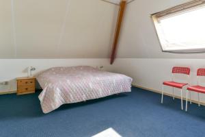 Baaiduinenvakantiehuis op terschelling的一间卧室配有一张床和两张红色椅子