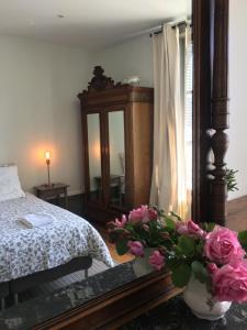 Boën家庭豪宅住宿加早餐旅馆的一间卧室配有一张床和一个花瓶,花朵粉红色