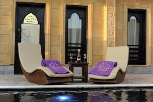 达哈布Casa d'Or Dahab PALAZZO的两把椅子,紫色靠垫,坐在游泳池旁