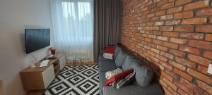 格但斯克Central Apartments Rajska的一间带砖墙和沙发的客厅