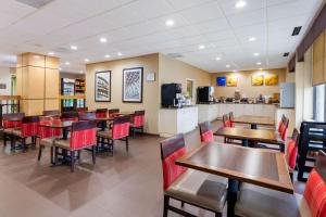 达拉姆Comfort Inn & Suites Durham near Duke University的餐厅设有木桌和红色椅子