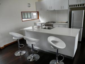 富良野Furano Lodge 10的厨房配有白色的柜台和2张凳子