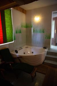 卢斯泽格尼扎弗拉尼克旅馆的带浴缸的浴室,墙上有草