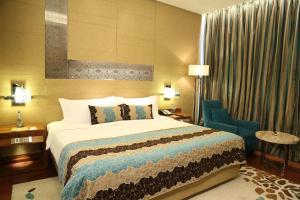 古尔冈泰姬陵市中心古鲁格兰姆酒店的酒店客房,配有一张床和一张蓝色椅子