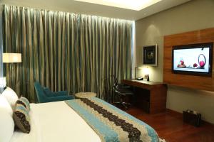 古尔冈泰姬陵市中心古鲁格兰姆酒店的配有一张床和一台平面电视的酒店客房