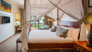 奔巴岛Avani Pemba Beach Hotel的一间卧室配有一张天蓬床和一张书桌