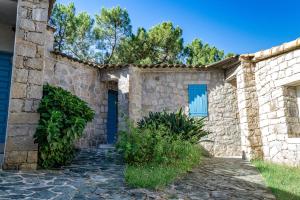 SollacaroRésidence de Filitosa - Le Torréen的一座带蓝色门和树木的石头房子