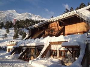 阿塞尔吉尼多阿齐拉酒店的一座被雪覆盖的建筑,背景是群山