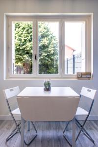 布隆Maisonnette avec jardin, parc du chêne (tram T5)的配有两扇窗户的客房内的白色桌子和椅子