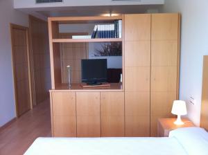 拉斯·罗萨斯·德·马德里塔尔特索斯公寓式酒店的一间卧室设有大型木柜和电视