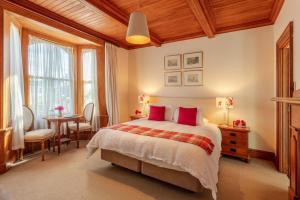阿卡罗阿法国湾旅馆的一间卧室配有一张带红色枕头的床和一张桌子