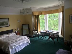 埃尔金Kilmorie House的一间卧室配有一张床、一张桌子和一个窗户。