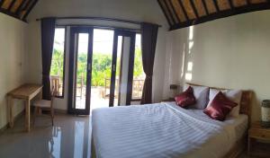 珀尼达岛Bukit keker cottage的一间卧室设有一张床,并有通往阳台的门