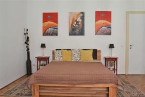 布达佩斯Paprika Apartment Grand的一间卧室配有一张床,墙上挂着一些绘画作品