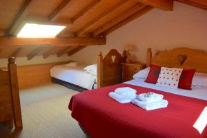 梅杰夫Chalet Roseau的一间卧室配有两张带红色床单和毛巾的床。