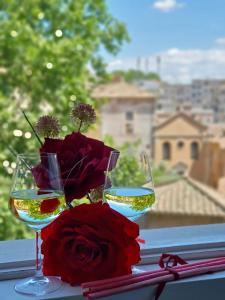 罗马Glory House Trastevere的桌子上放着两杯葡萄酒和一瓶鲜花