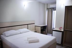 CeilândiaHOTEL VINTE UM的卧室配有白色的床和2条毛巾